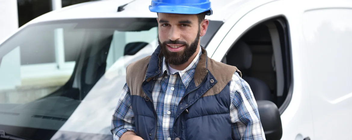 Man in hard had standing in front of small white van