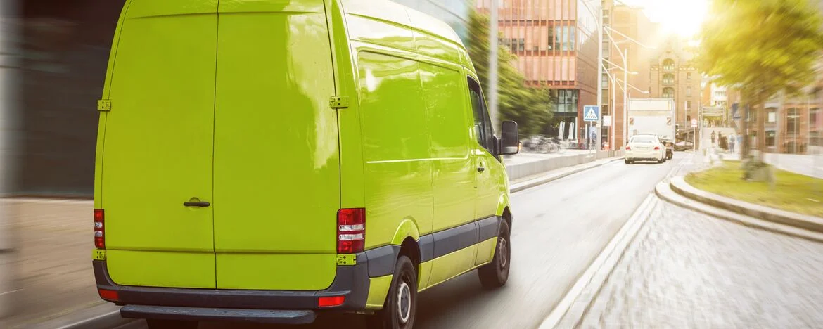 Green cargo van driving in a city