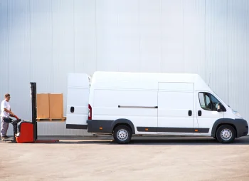 Man using forklift to load large white van