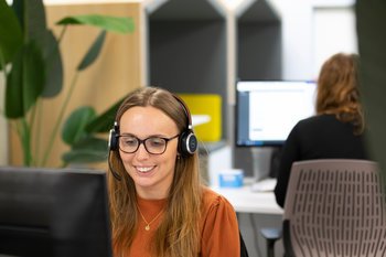 Female Vanparison team member at her desk wearing a headset